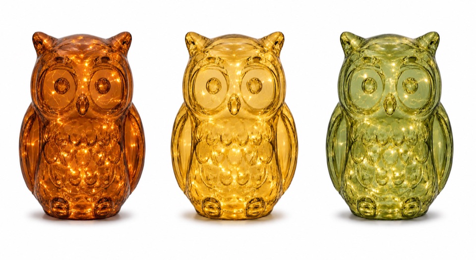 Three illuminated owl-shaped glass lights in amber, honey, and olive